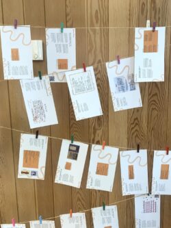 Some of the previous winning entries suspended on string. Each entry is printed on an A5 white postcard, attached to the string with a colourful peg.